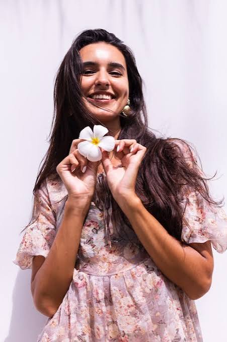 Smiling woman holding a flower, representing the genuine connections people look for when choosing a video calling app